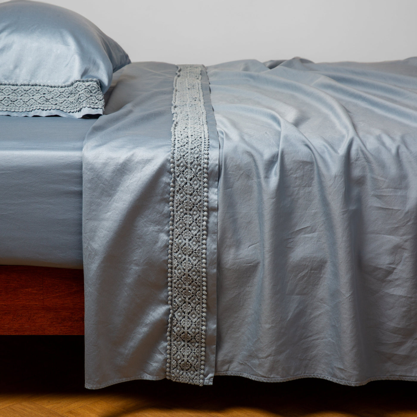 Bella Notte Bria flat sheet in Tahoe Blue, showing ornate lace trim detail down center fold.