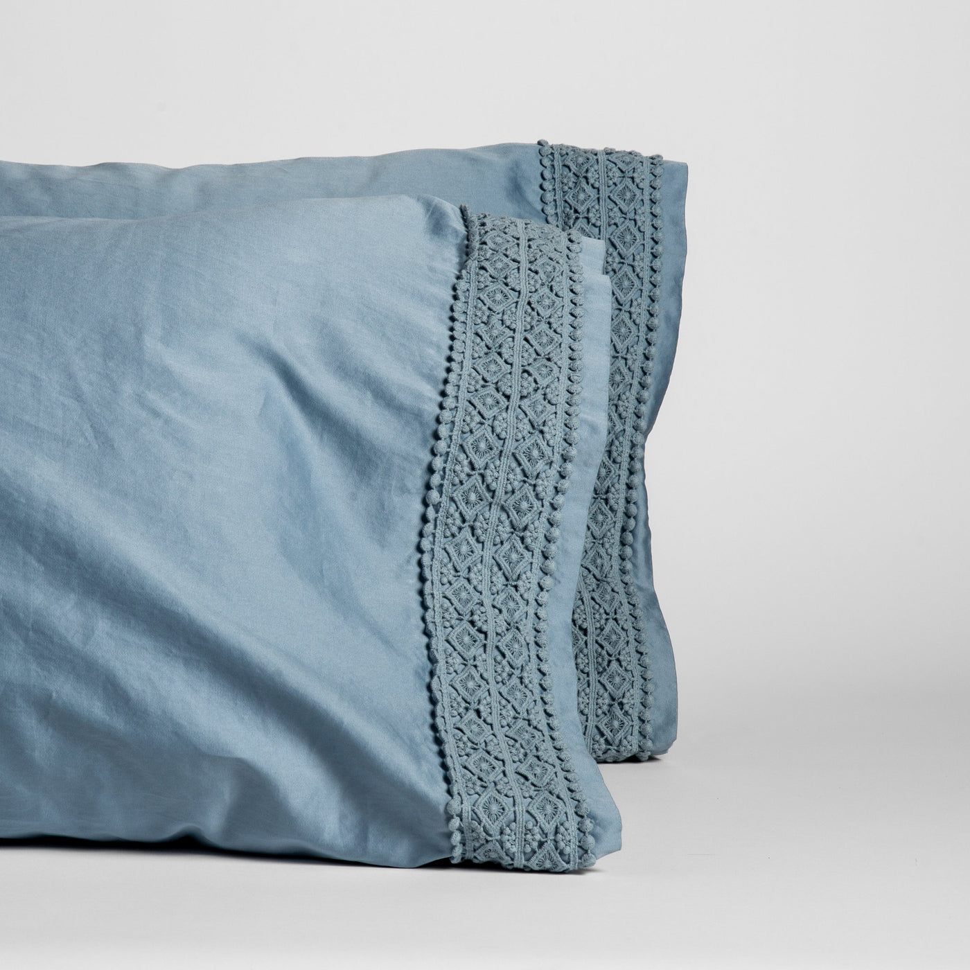 Close-up of Bria pillowcase crochet lace trim and pom-pom edge detail in Tahoe Blue.