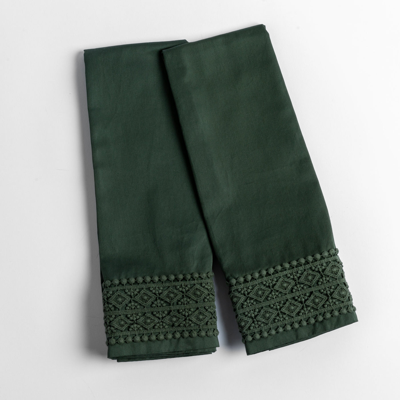Close-up of Juniper Bria pillowcase hem with geometric lace trim and pom-pom border detail.