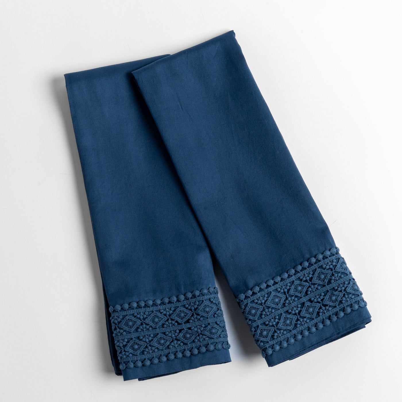 Midnight pillowcase hem detail showing diamond lace trim and pom-pom border.