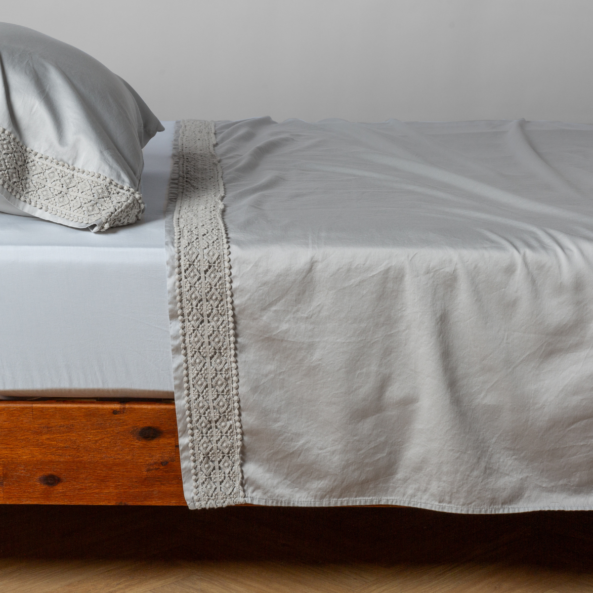 Bella Notte Bria flat sheet in Cloud, showing crochet lace trim detail draped over bed.