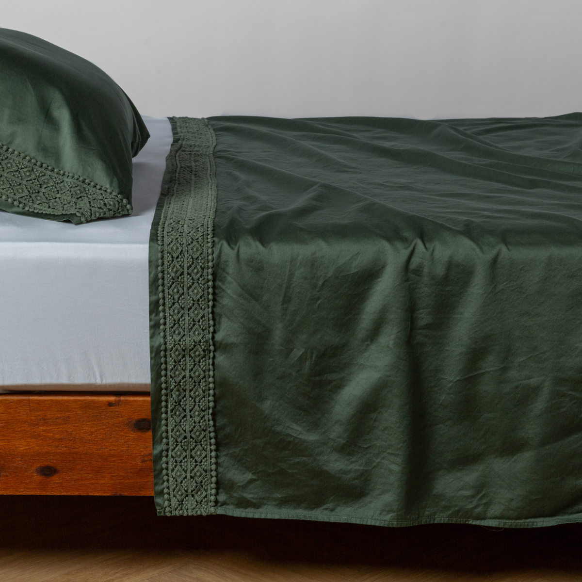 Juniper flat sheet with geometric lace trim, draped over a wood-frame bed.