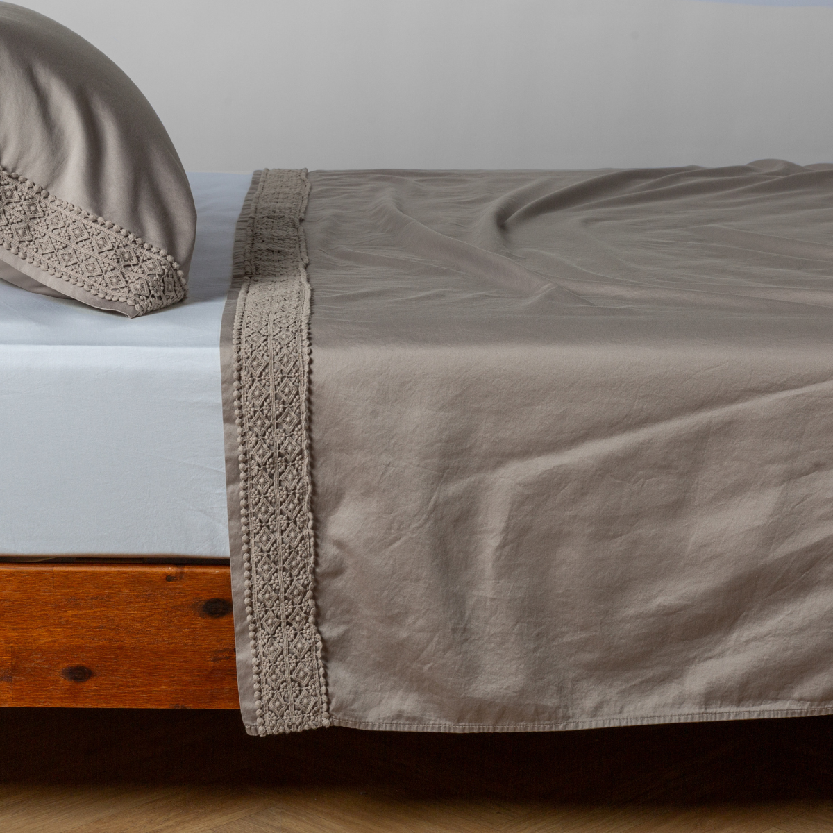 Fog flat sheet draped over bed, geometric lace trim detail along hem edge.
