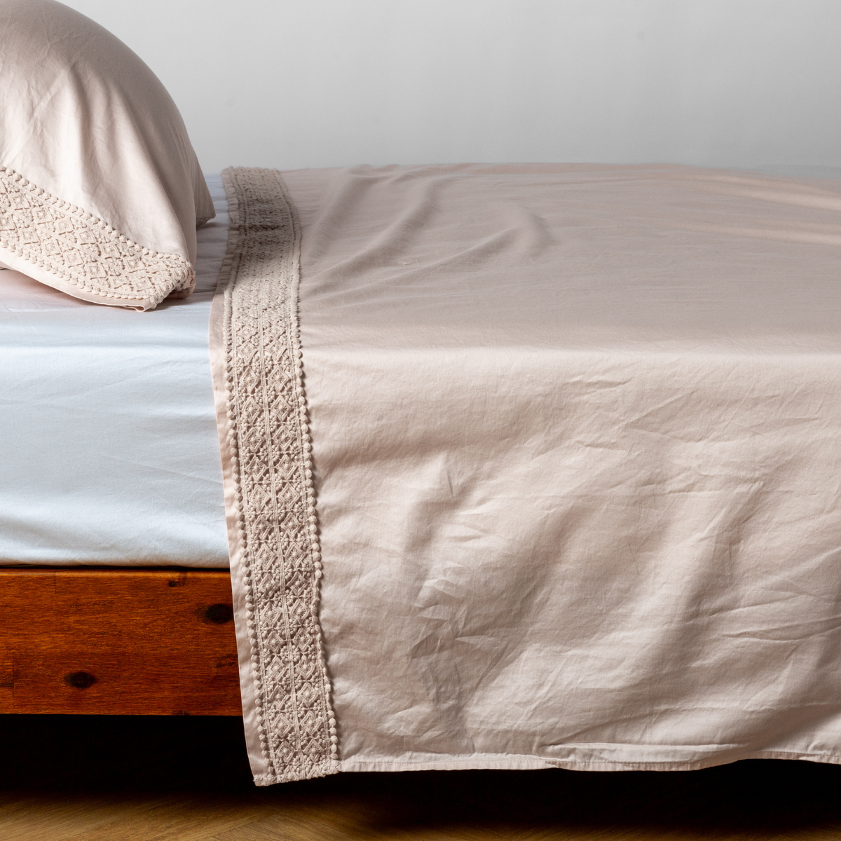 Pearl Bella Notte Bria flat sheet on bed, crochet lace trim detail along edge.