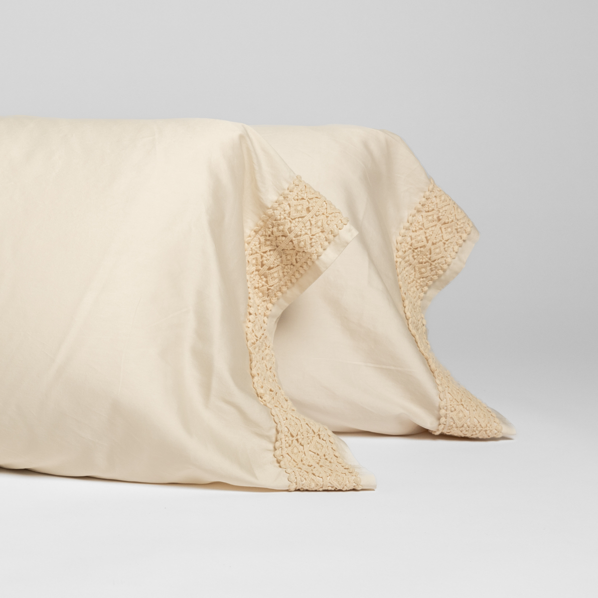 Close-up of Natural Bella Notte Bria pillowcase corners showing intricate crochet lace trim detail.