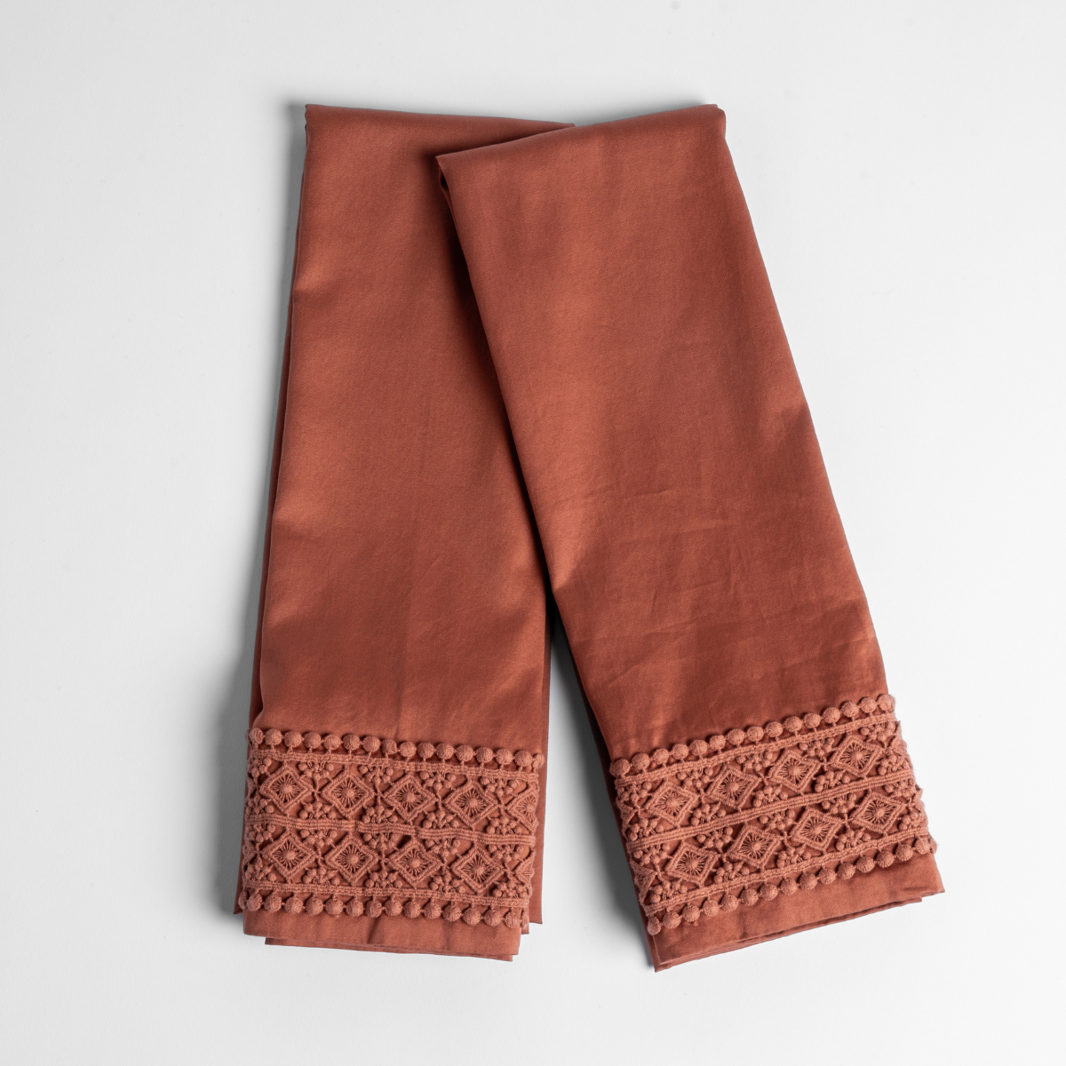 Hem detail of Bella Notte Bria pillowcase in Autumn, showing geometric lace trim and pom-pom edging.