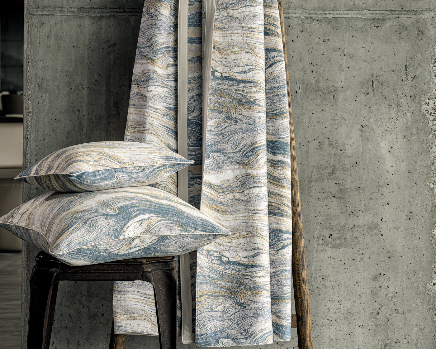 Marble-patterned cushions and a curtain against a concrete wall
