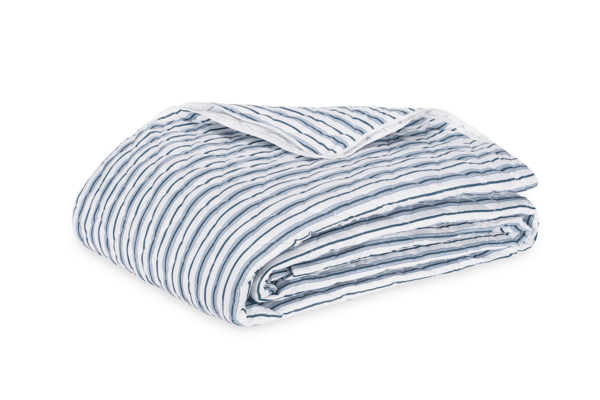 Matouk Calypso quilt in white and slate blue ticking stripes, folded flat.