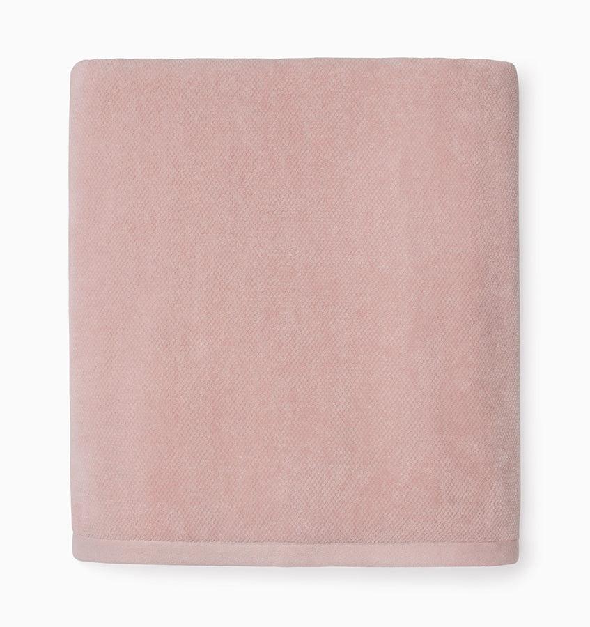 Close-up of folded blush cotton bath towel with subtle herringbone texture.