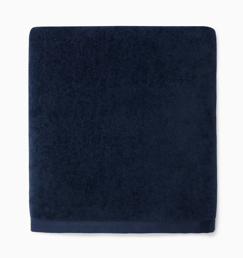 Navy terry cloth bath towel folded flat, showing textured loop weave and solid border.