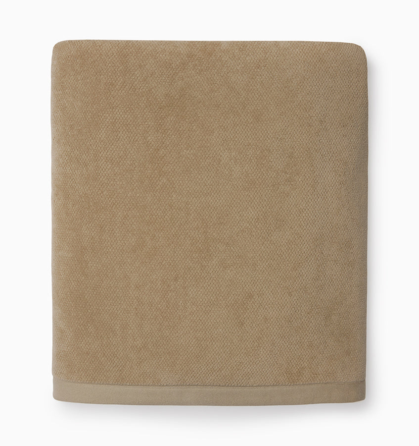 Folded camel-toned terry bath sheet with woven border detail against white background.