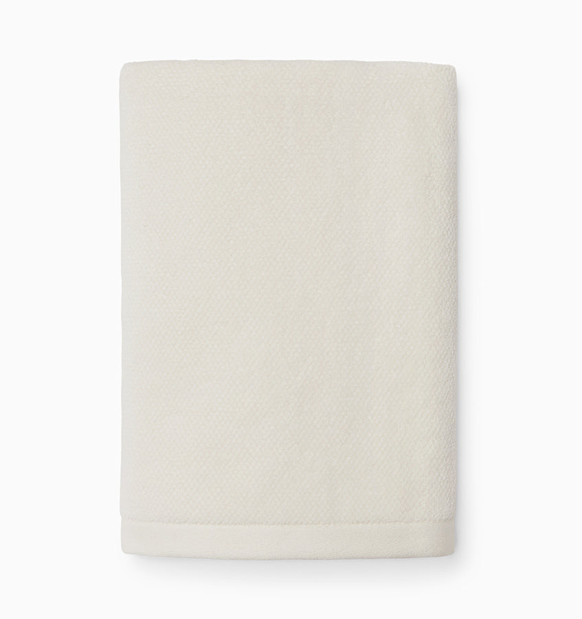 Ivory hand towel folded flat, showing subtle textured weave and contrast border detail.