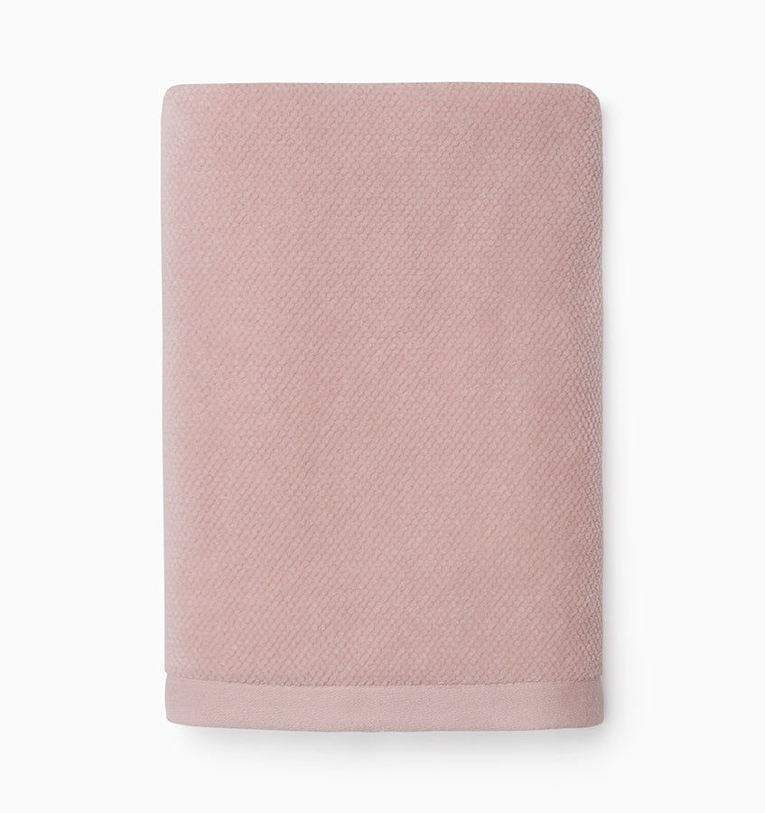 Folded blush cotton hand towel showing textured diamond weave and contrast border detail.