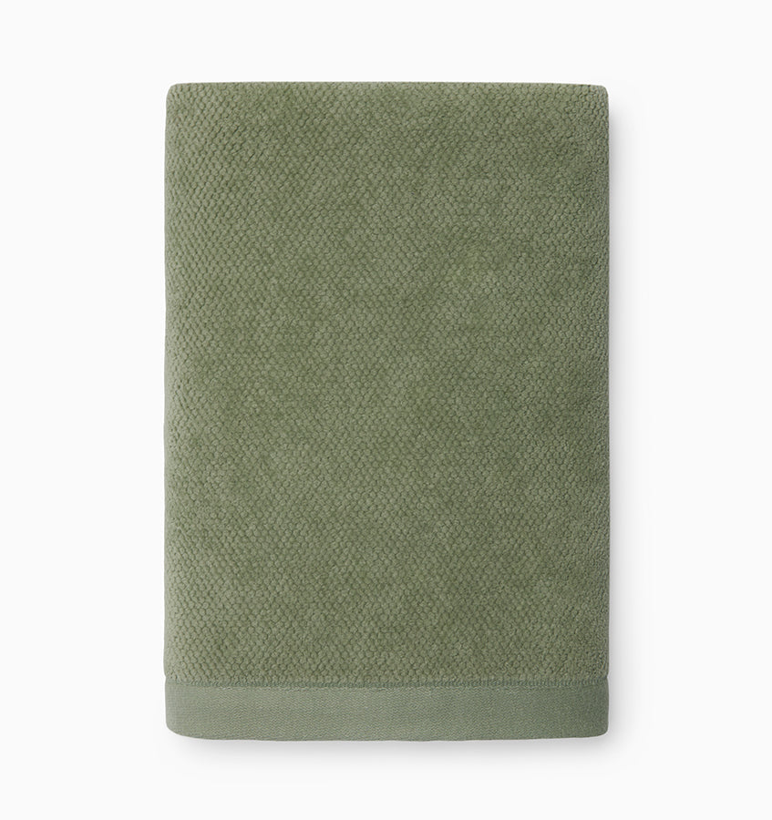 Folded sage green hand towel showing textured cotton weave and contrast border hem.