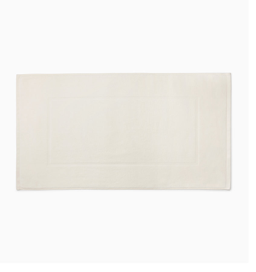Ivory cotton tub mat with inset border detail, flat lay on white background.