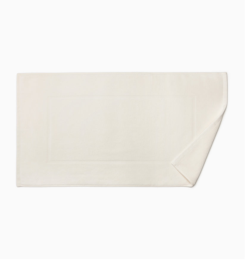 Corner fold detail on ivory Sferra Canedo Nuovo tub mat with woven border.