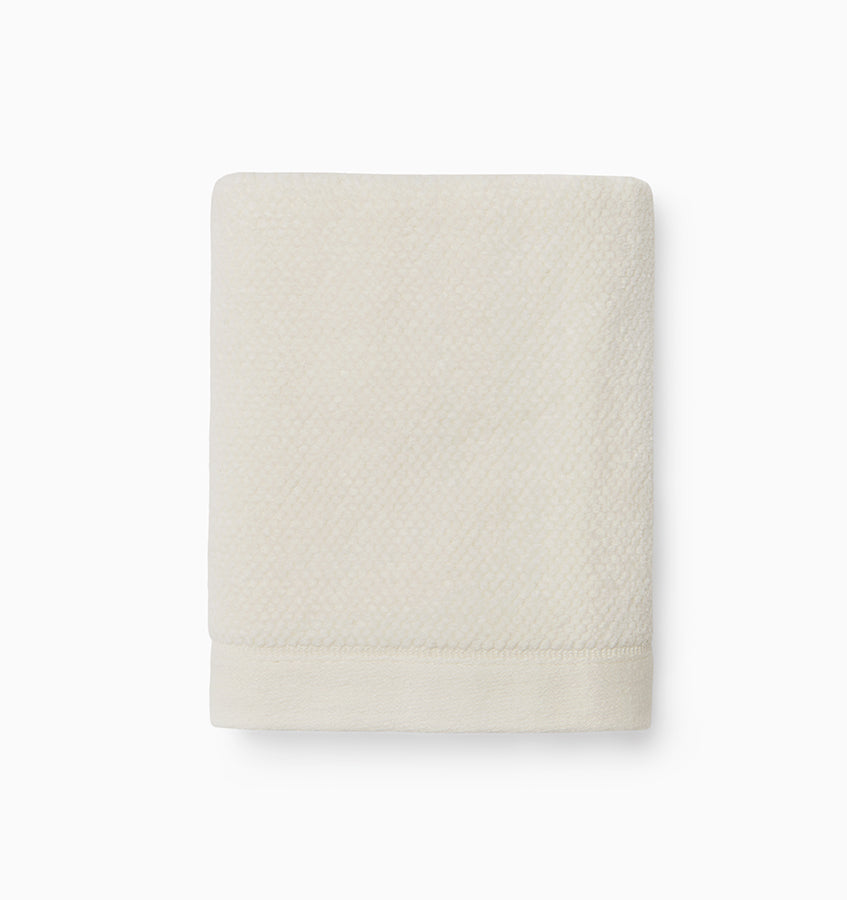 Folded ivory Sferra Canedo Nuovo washcloth showing textured cotton weave detail.