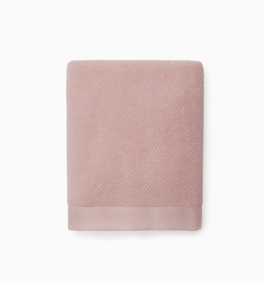 Folded blush Sferra Canedo Nuovo washcloth showing dobby-weave texture and woven border.
