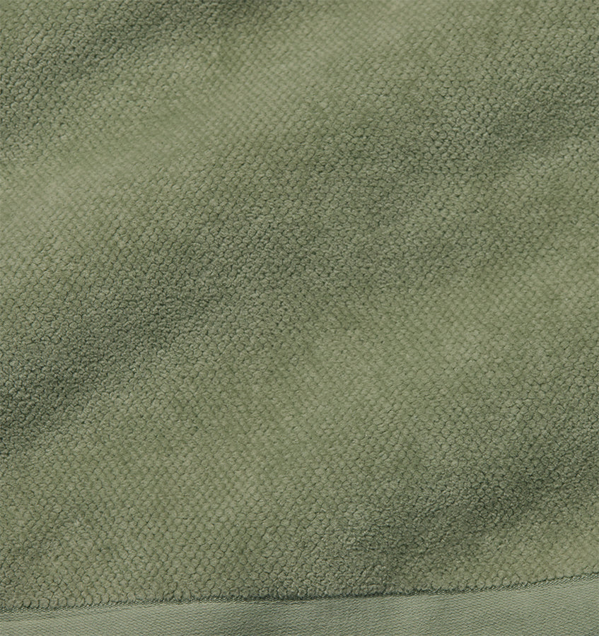 Close-up of sage green terry cloth texture with woven border detail.