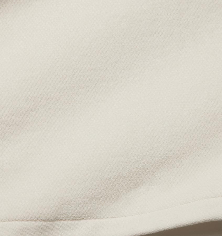 Close-up of ivory cotton tub mat surface showing textured waffle weave detail.