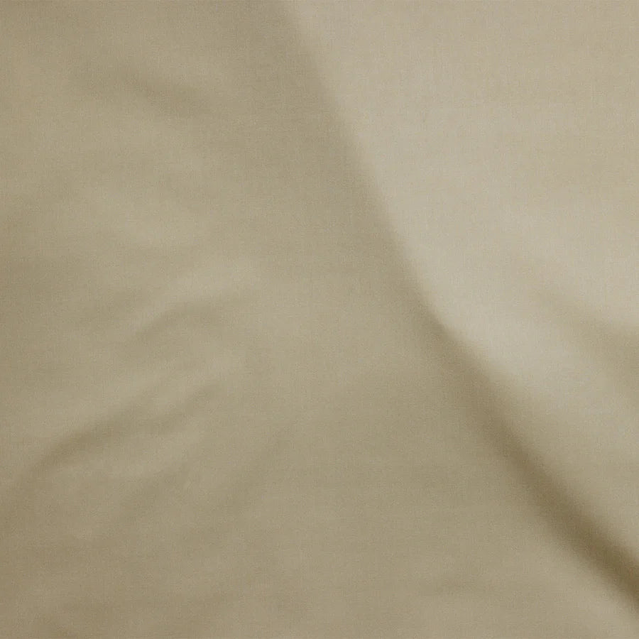 A close-up of the SDH Capri Percale pillowcase shows its smooth beige cotton percale fabric, featuring slight wrinkles, soft shadows, and subtle color variations.