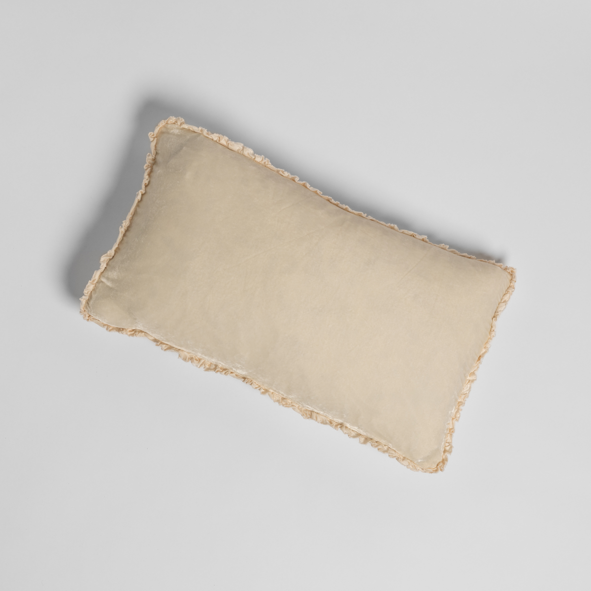 Overhead view of Crema Carmen throw pillow with fringe trim edging all sides.