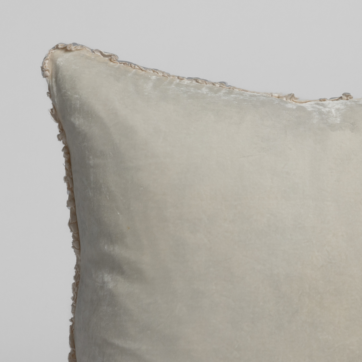 Close-up of Crema velvet sham corner showing tonal fringe trim detail.