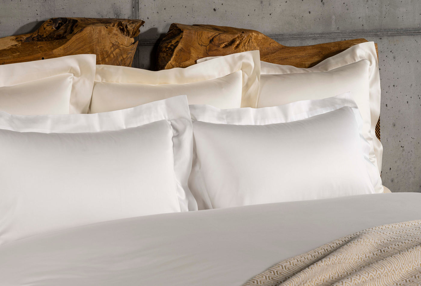Close-up of Celso de Lemos Amanda ivory flat sheet layered with white pillowcases on a styled bed.