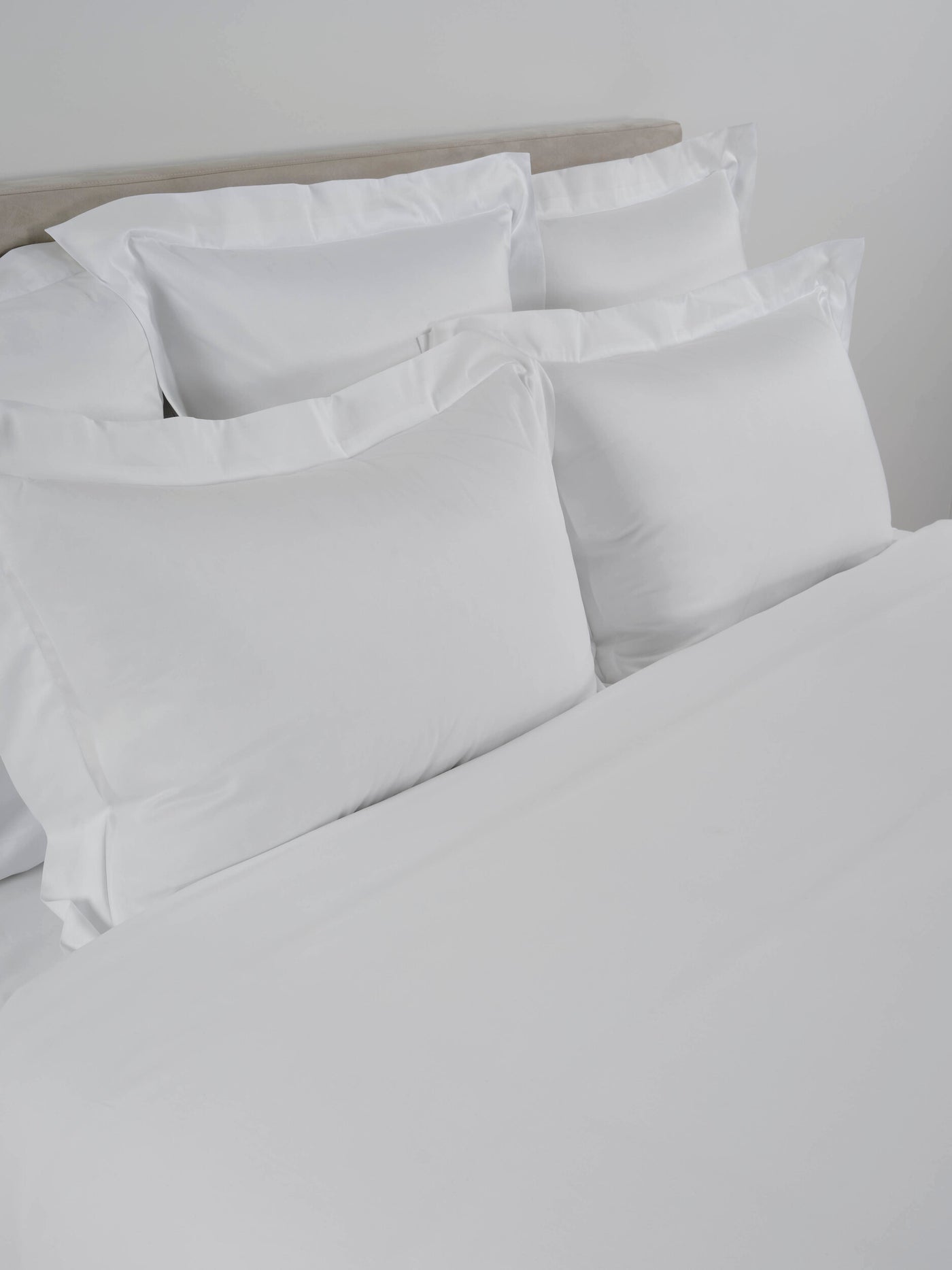 Celso de Lemos Amanda white cotton flat sheet styled on a bed with matching pillows.