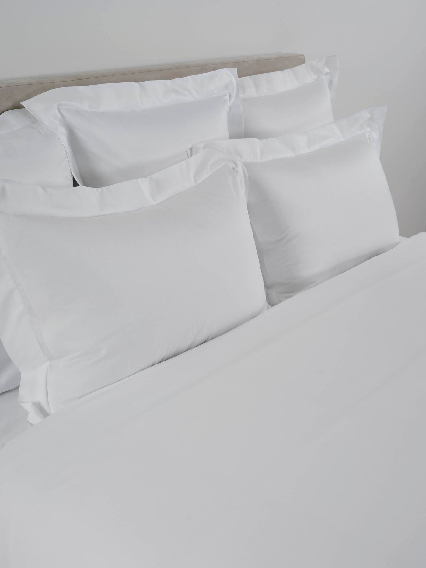 Close-up of white Amanda fitted sheet with crisp hotel-style pillowcases on a made bed.
