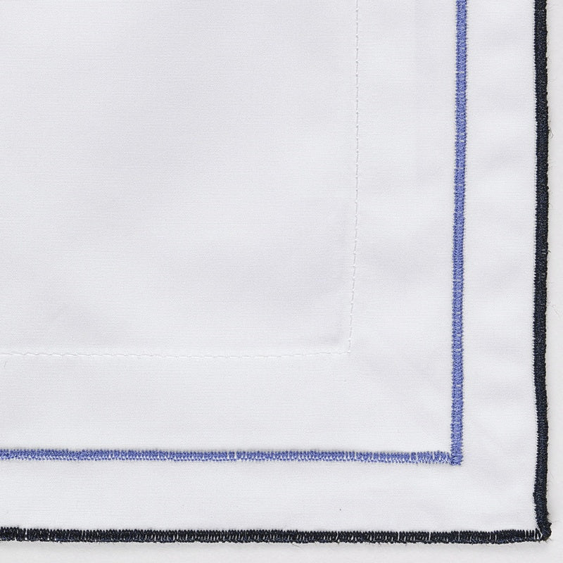 Close-up of white fabric with double blue and black embroidered trim, featuring Areo Pillowcase by Celso de Lemos available at Linen Society.