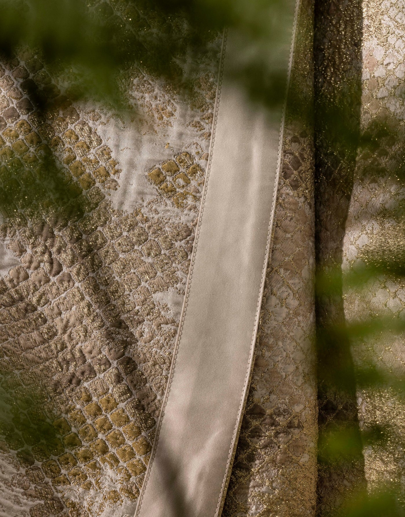 Close-up textured fabric with a damask pattern in gold and cream, featuring a neutral satin ribbon, Australia Bed Cover by Celso de Lemos available at Linen Society.