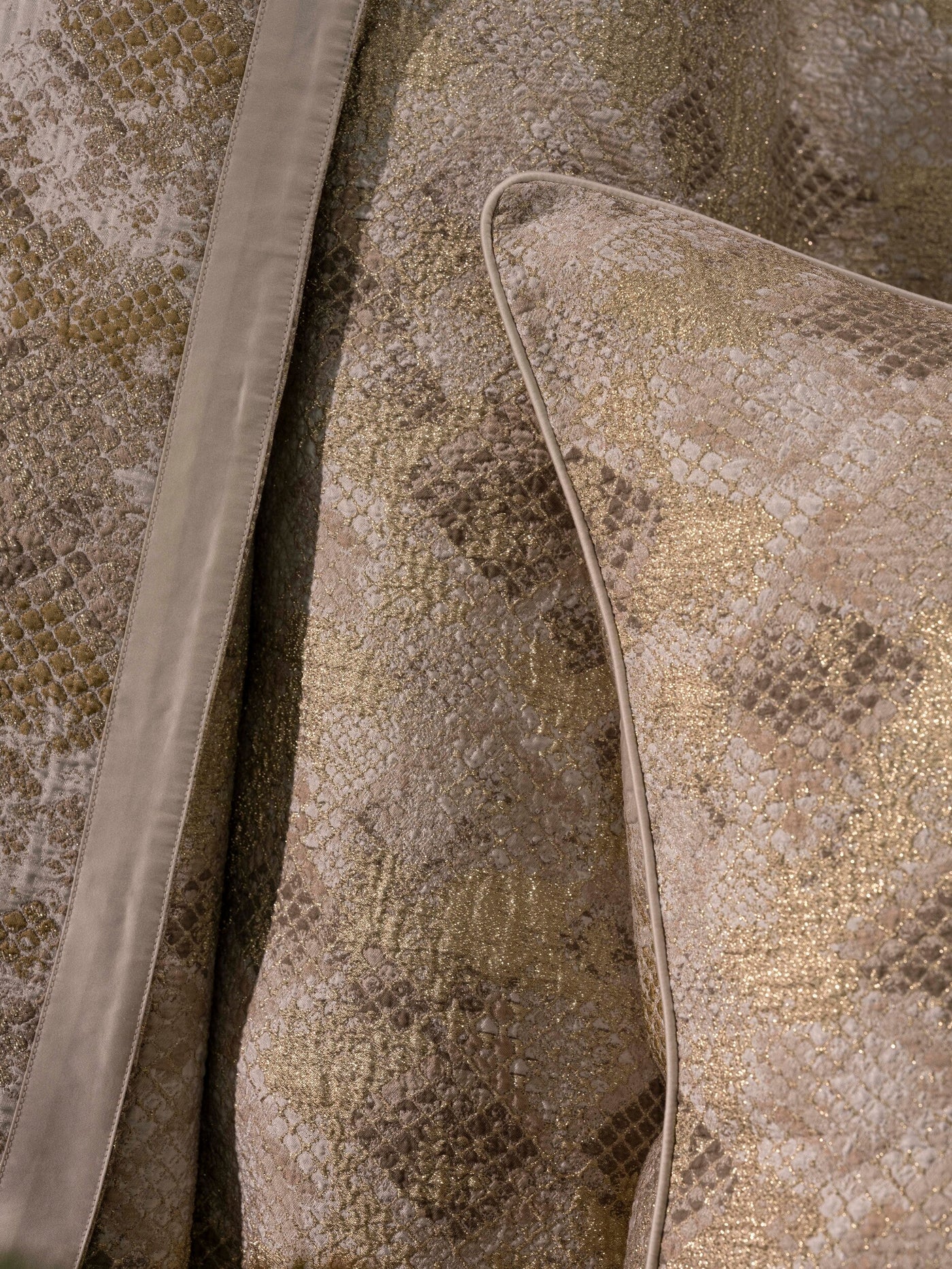 Close-up of a shimmering gold and cream textured jacquard fabric with a piped edge, featuring Australia Pillow Cover by Celso de Lemos available at Linen Society.