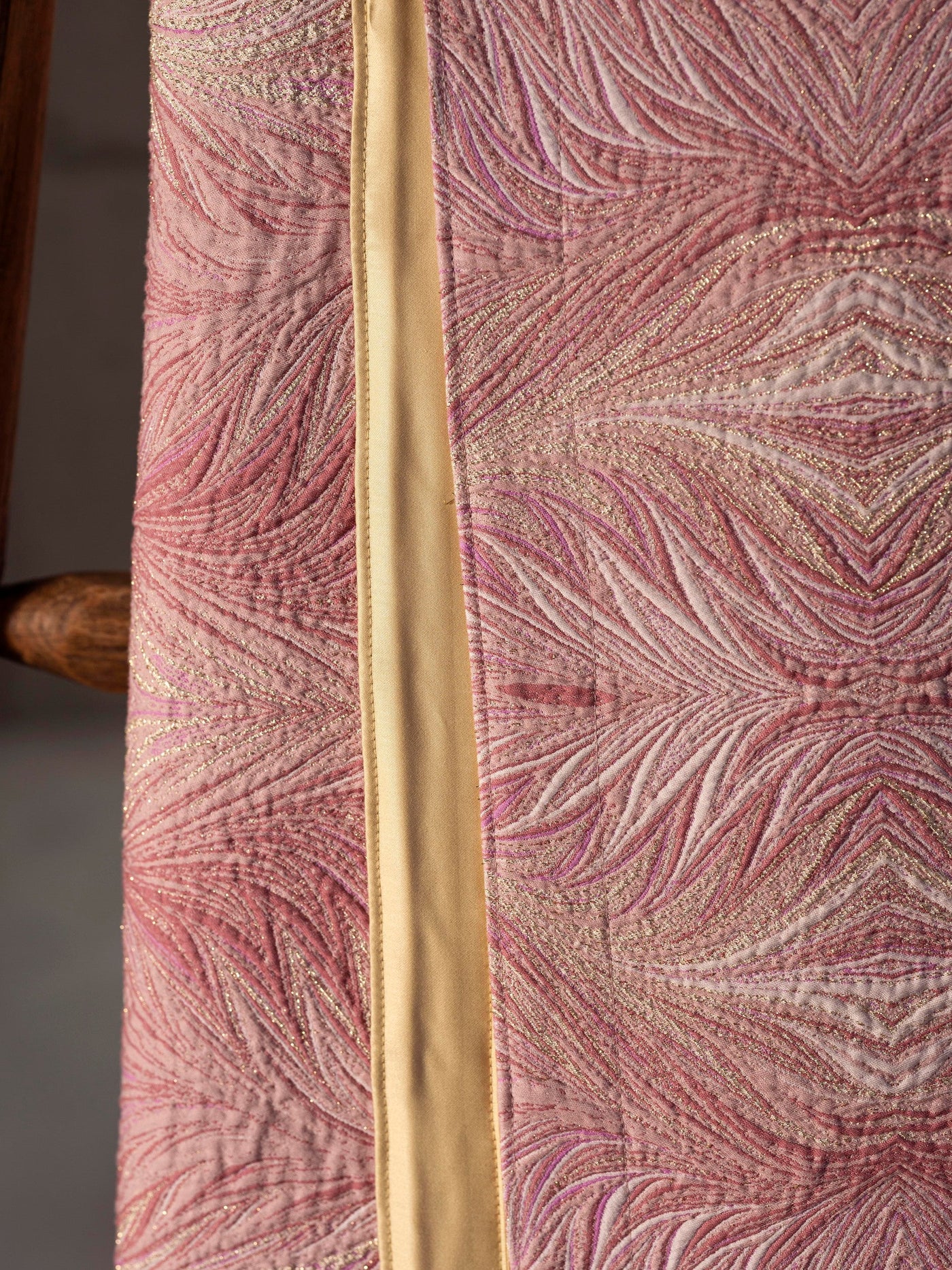 Close-up of a pink bed cover with a textured feather pattern and metallic gold accents, featuring Boheme Bed Cover by Celso de Lemos available at Linen Society.