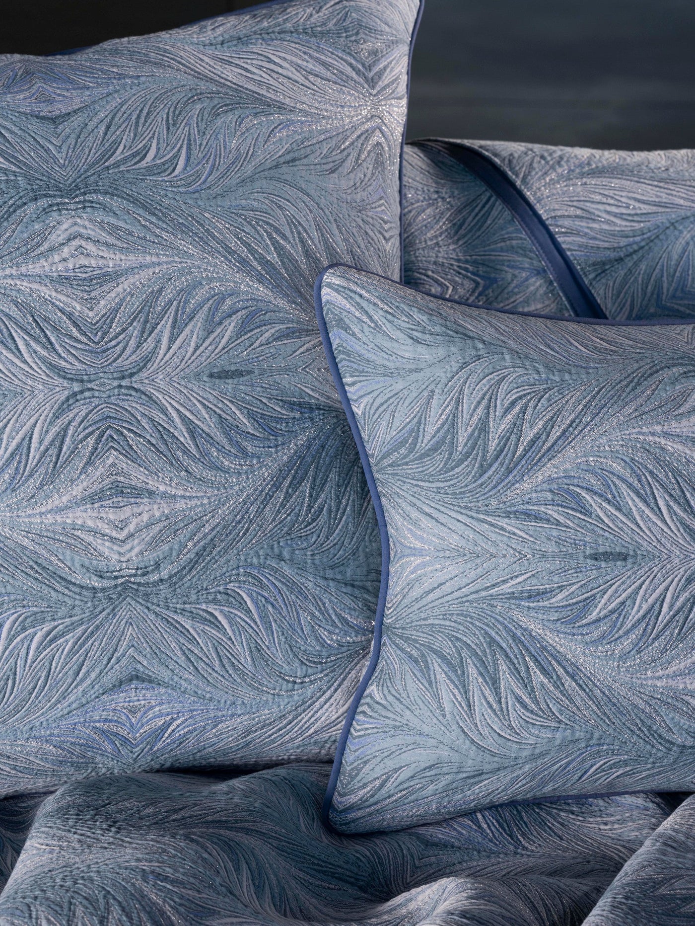 Close-up view of pillows in shades of blue with a textured, abstract feather pattern and subtle shimmer, featuring Boheme Pillow Cover by Celso de Lemos available at Linen Society.