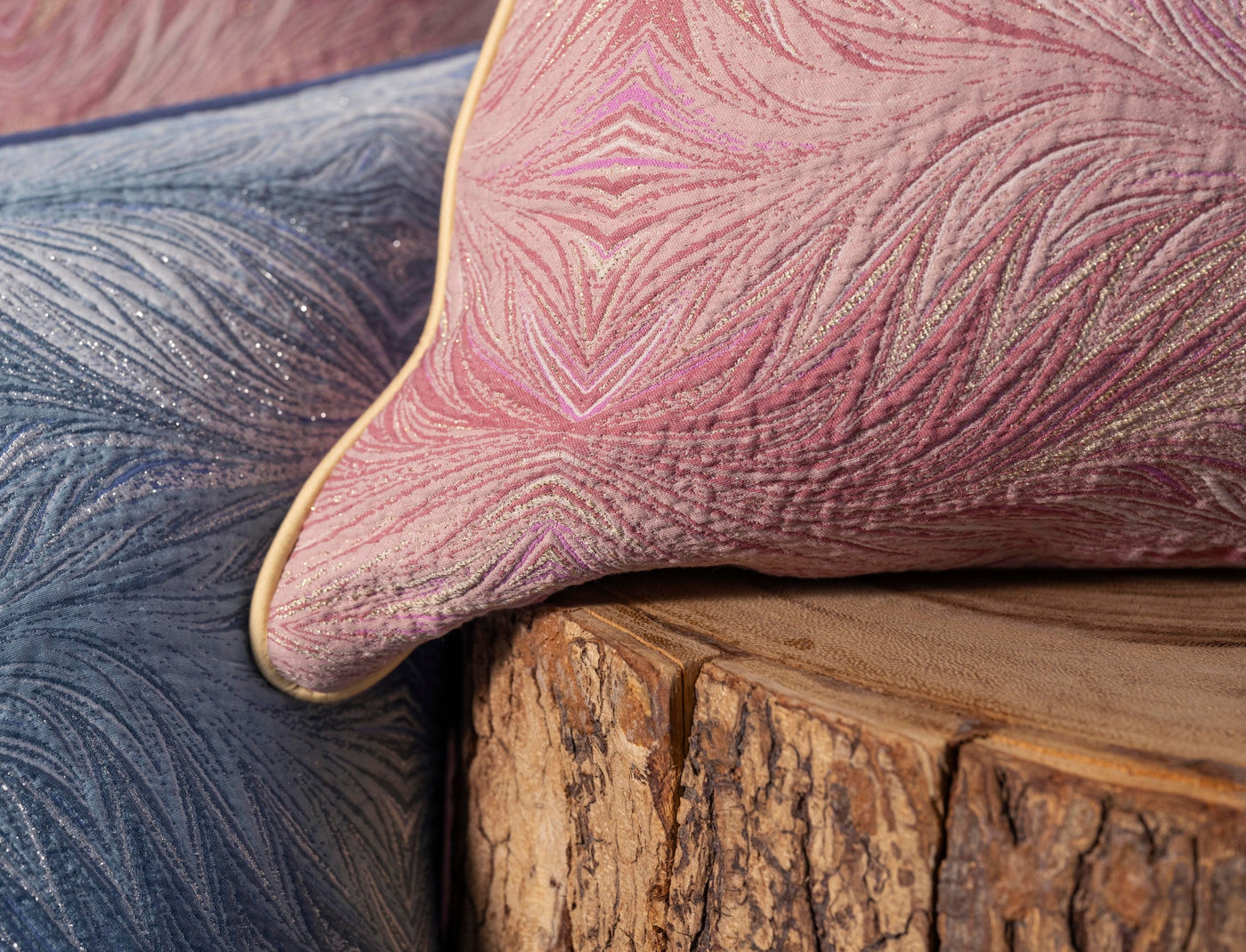 Close-up of textured pink and blue pillow covers with subtle metallic threads on a rustic wooden surface, featuring Boheme Pillow Cover by Celso de Lemos available at Linen Society.