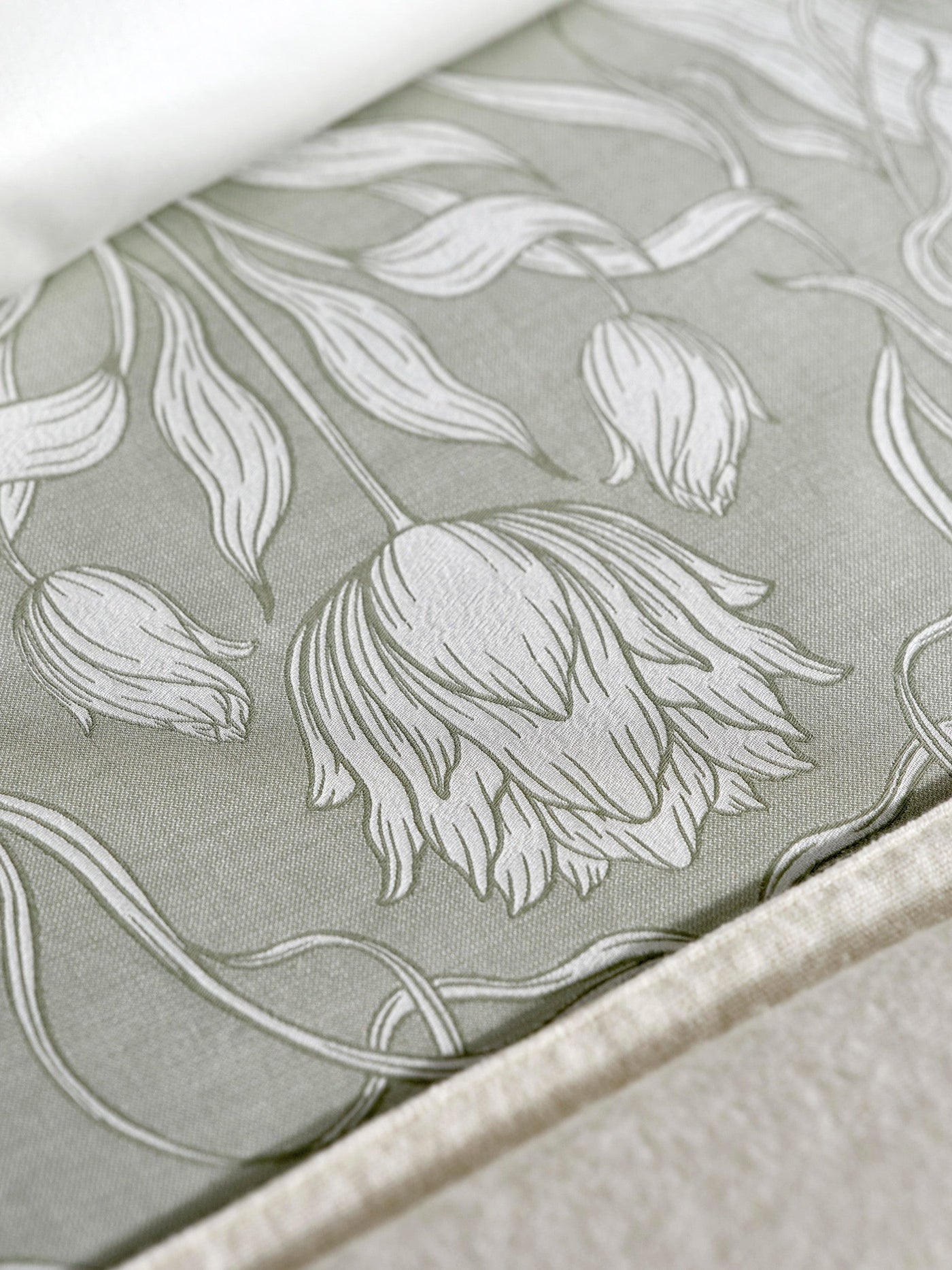 Close-up of a pale green fabric with a raised white floral damask pattern, featuring the Botanica Pillowcase by Celso de Lemos available at Linen Society.