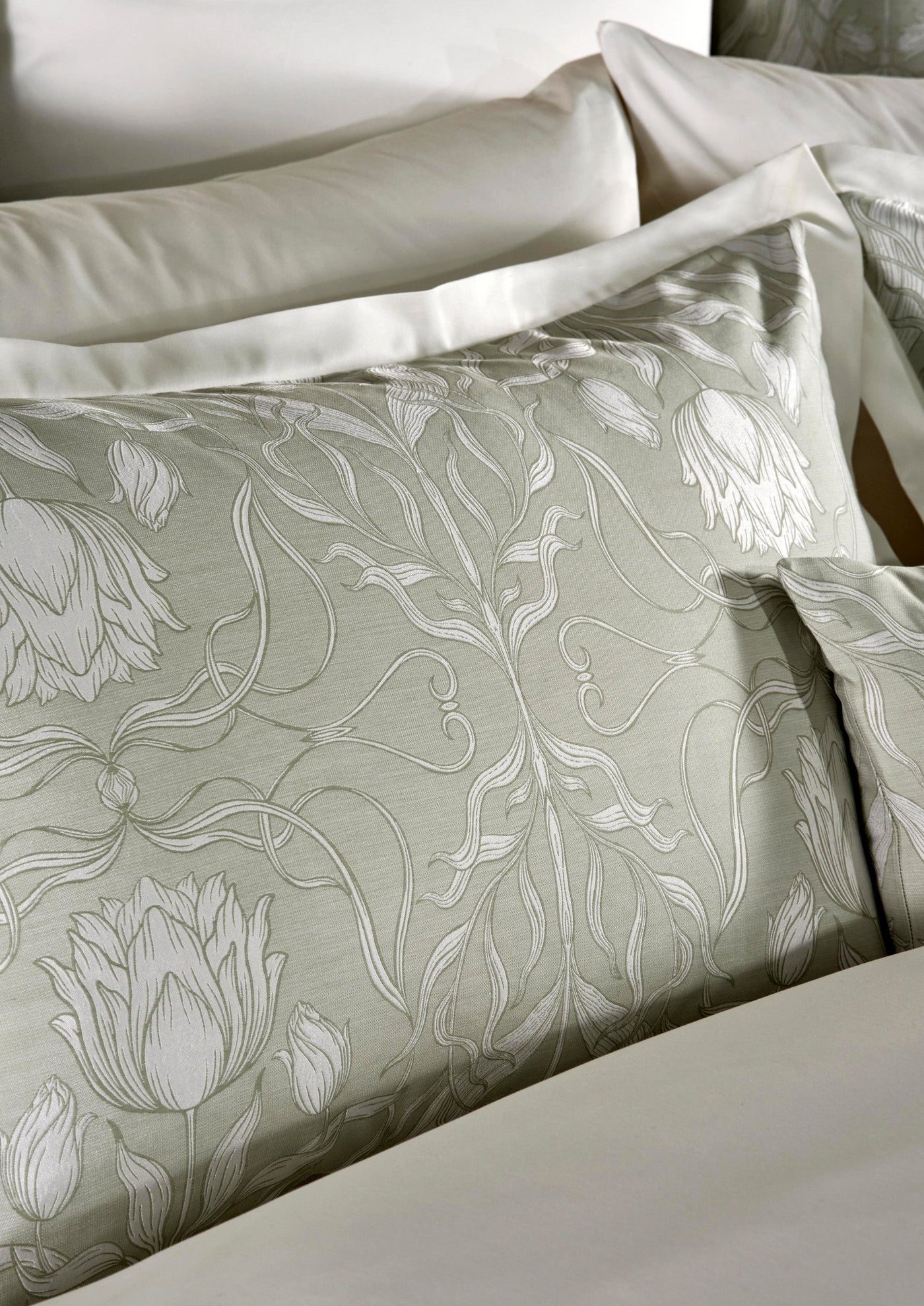 Soft sage green pillowcase with an intricate white floral vine pattern. featuring Botanica Pillowcase by Celso de Lemos available at Linen Society.