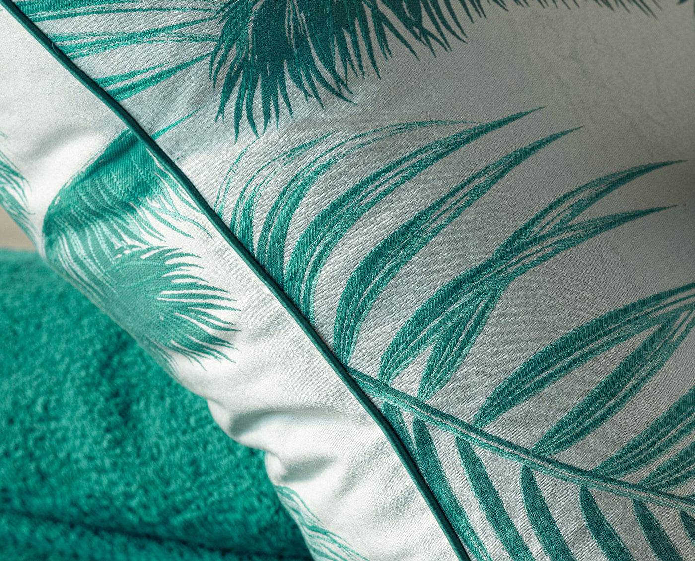 Close-up of a pillow with a white background and teal palm leaf pattern, featuring the Cabo Verde Pillow Cover by Celso de Lemos available at Linen Society.