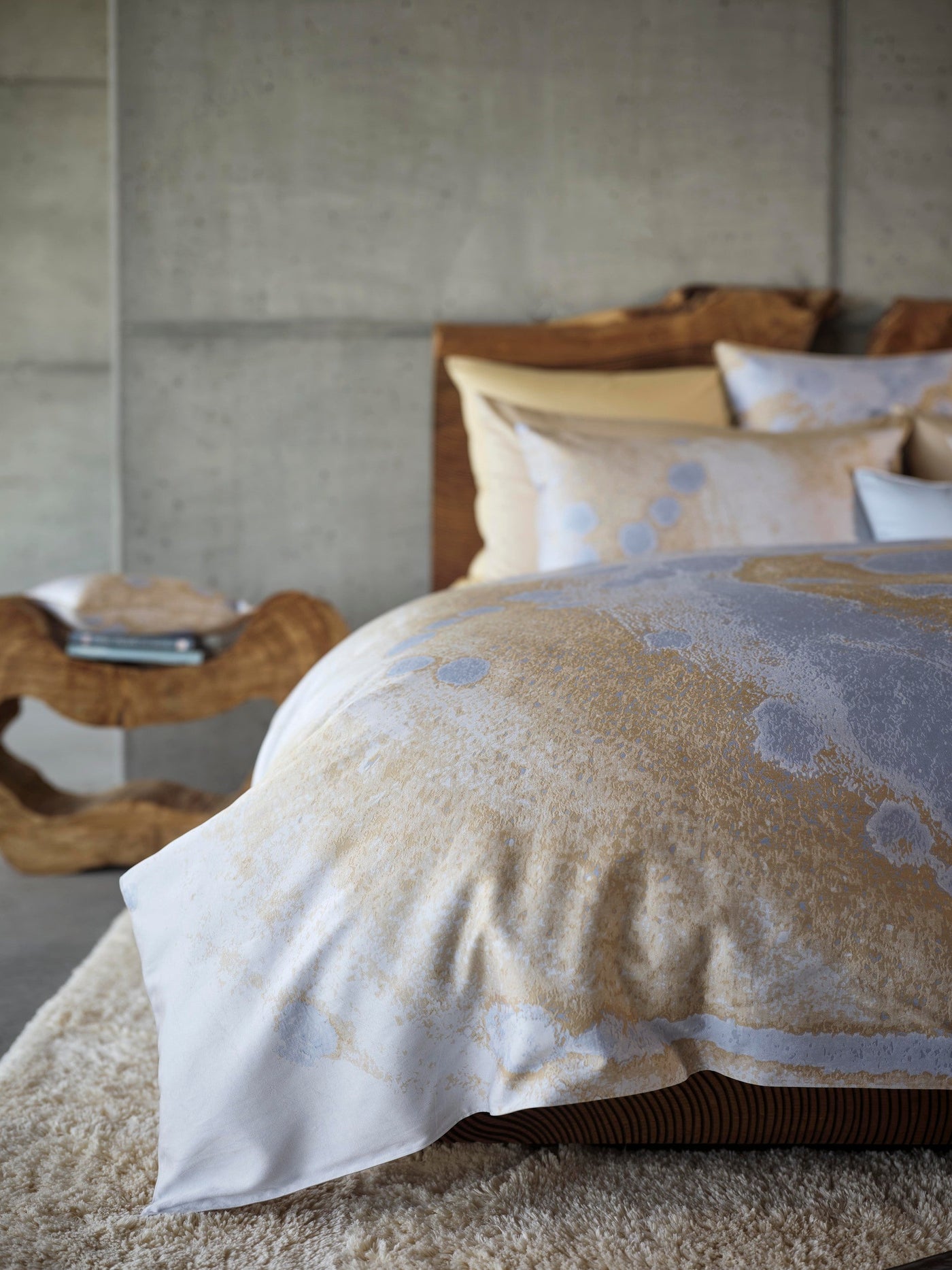 A bed with textured grey and gold pillowcases, featuring the Callisto Pillowcase by Celso de Lemos available at Linen Society.