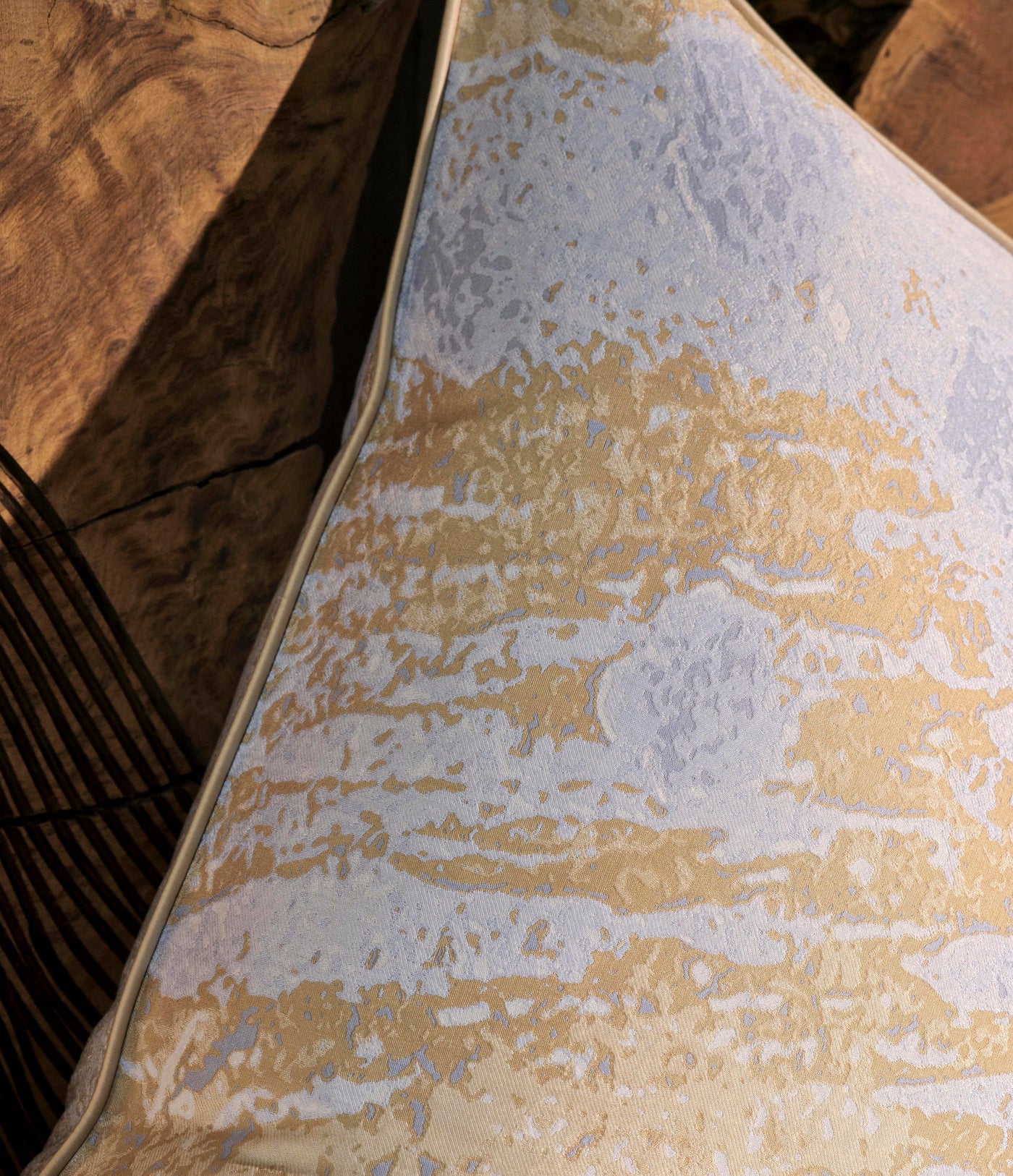A close-up of a textured pillowcase with abstract gold and light blue patterns, featuring Callisto Pillowcase by Celso de Lemos available at Linen Society.