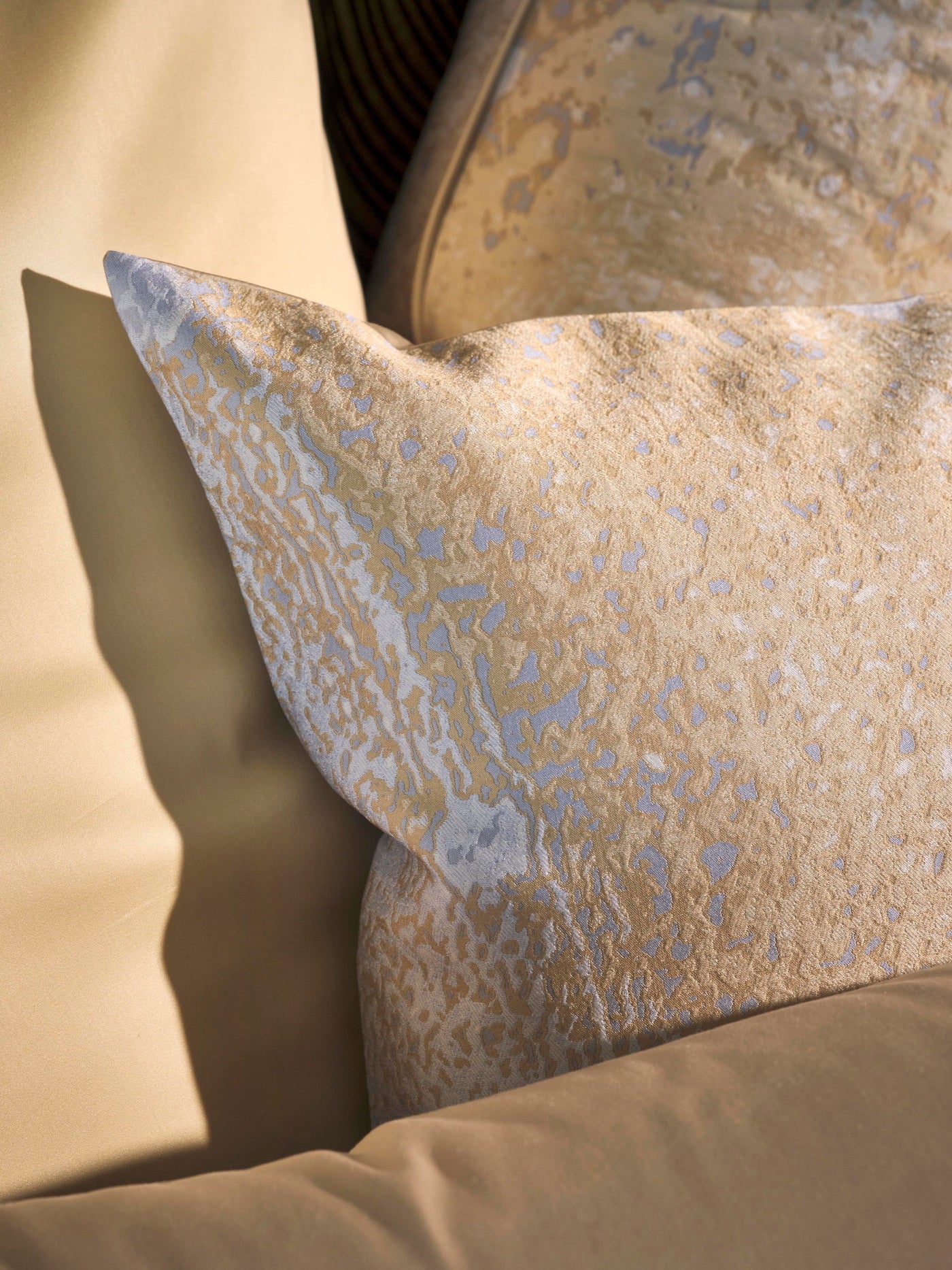 Gold and light blue patterned Pillowcase rests on a tan pillow, featuring Callisto Pillowcase by Celso de Lemos available at Linen Society.