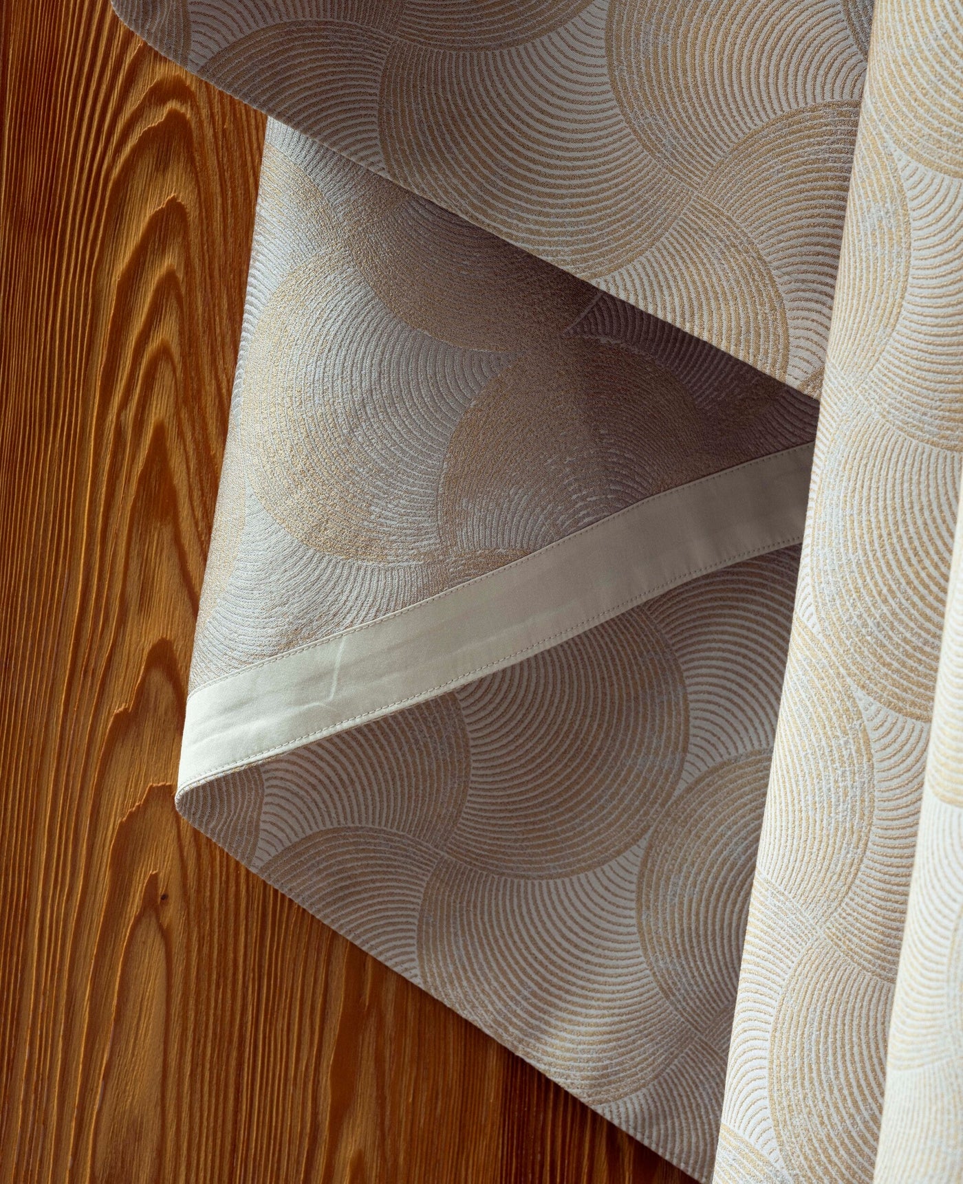 Drapery with a subtle sheen and a semicircular fan pattern in beige and gold, featuring Caviar Bed Cover by Celso de Lemos available at Linen Society.
