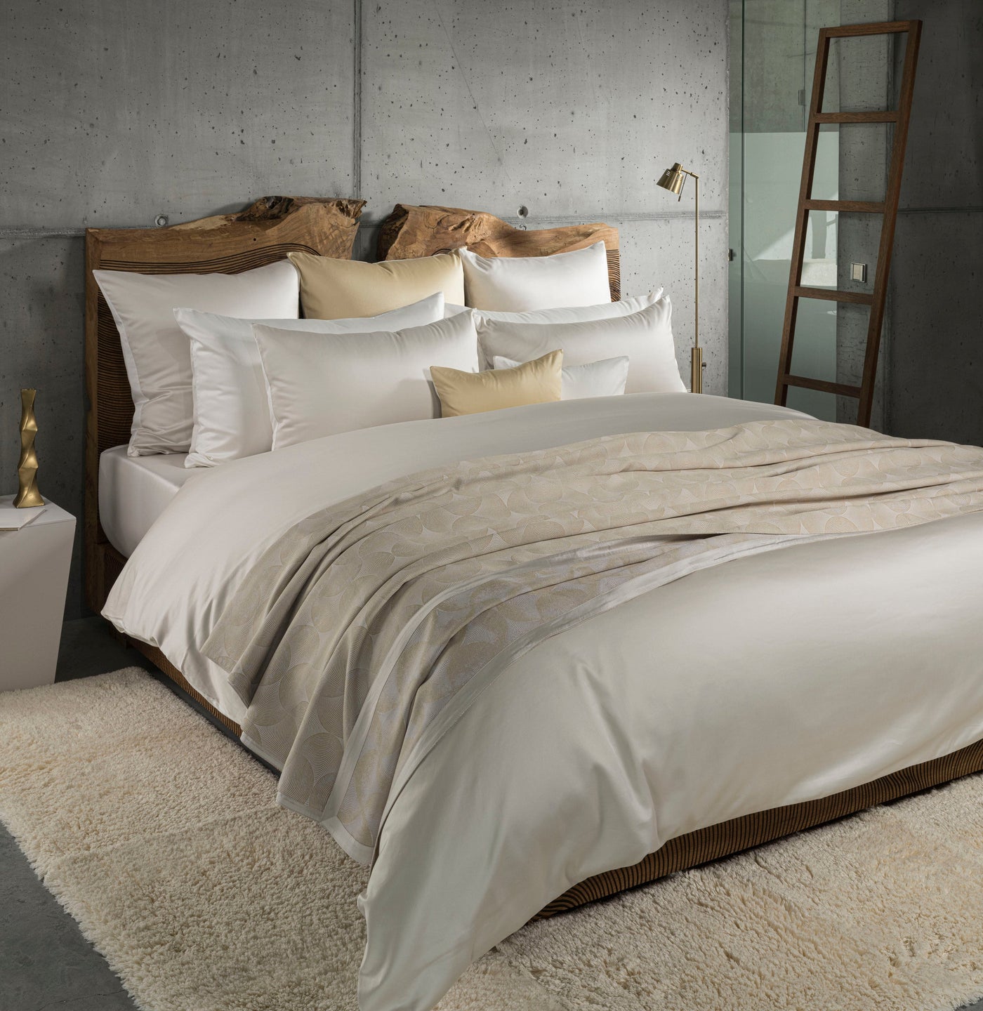 A luxurious bed is styled with cream-colored linens and a textured throw blanket, featuring Caviar Pillow Cover by Celso de Lemos available at Linen Society.
