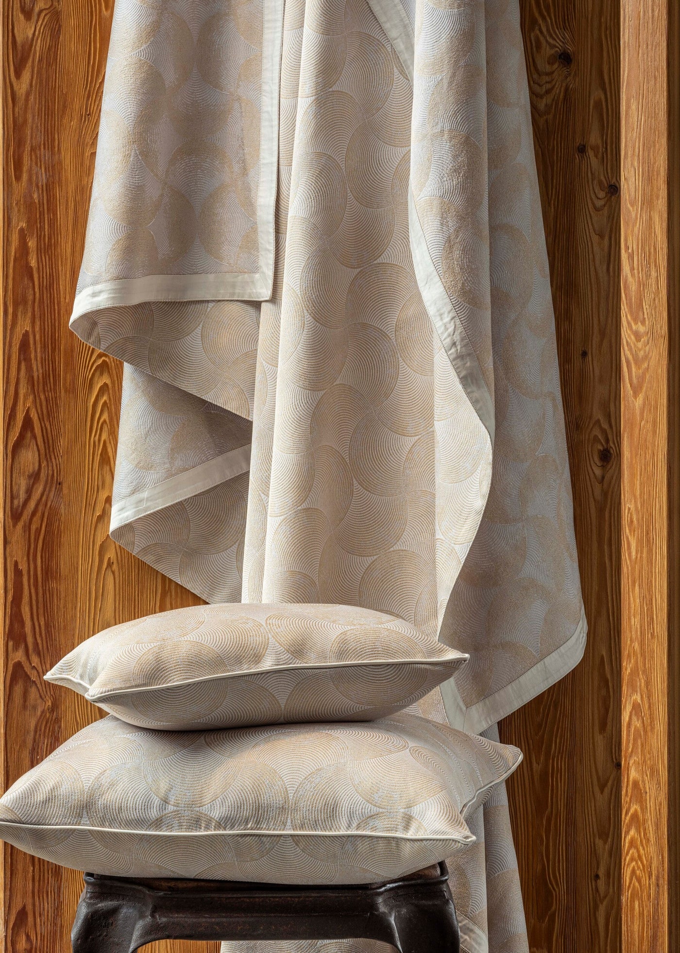 Two textured pillow covers with a geometric fan pattern are layered against a wooden background, featuring the Caviar Pillow Cover by Celso de Lemos available at Linen Society.