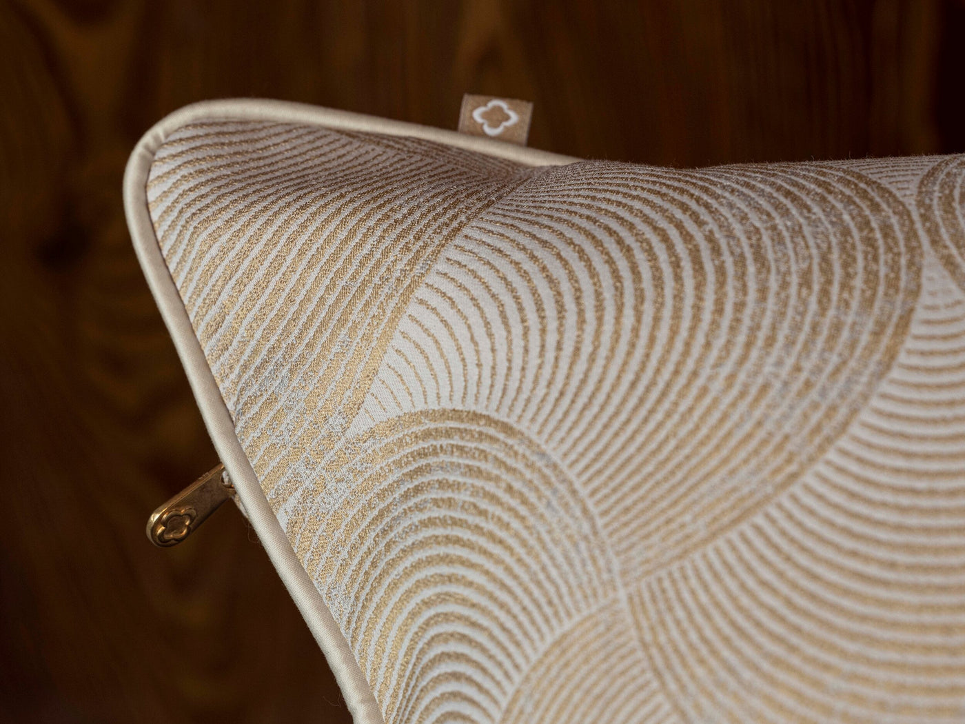 Close-up of a cushion with a gold fan pattern on a cream background, featuring Caviar Pillow Cover by Celso de Lemos available at Linen Society.