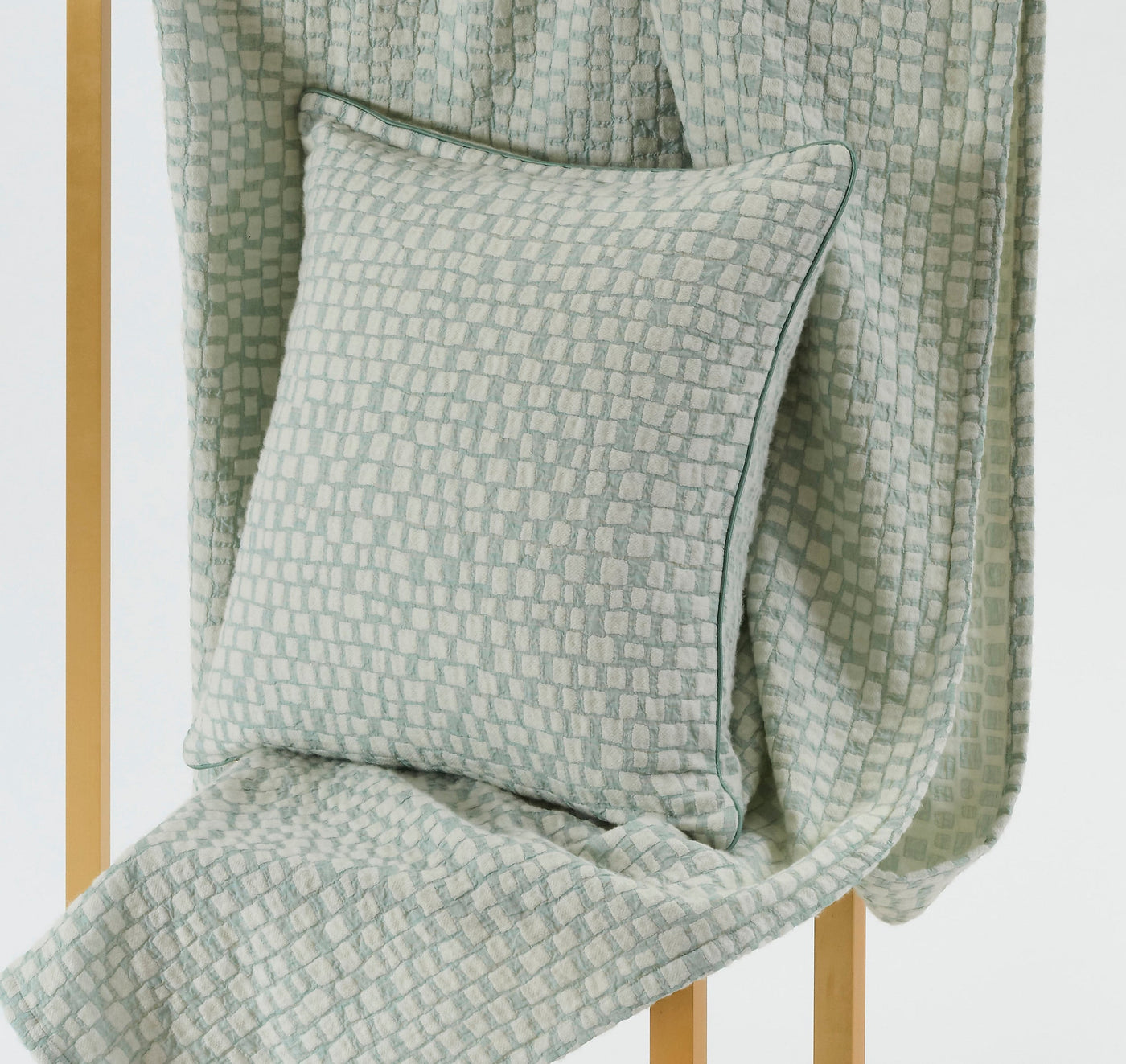 A textured, light blue and cream patterned throw draped over a wooden structure with a matching throw pillow resting on it, featuring City Pillow Cover by Celso de Lemos available at Linen Society.
