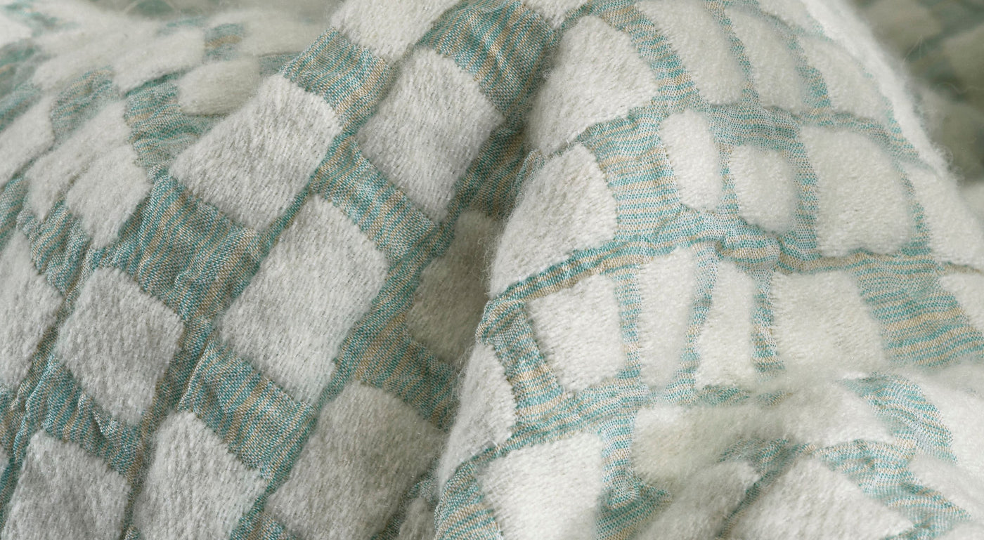 Close-up of a textured fabric with a geometric pattern in white and pale blue, featuring City Pillow Cover by Celso de Lemos available at Linen Society.