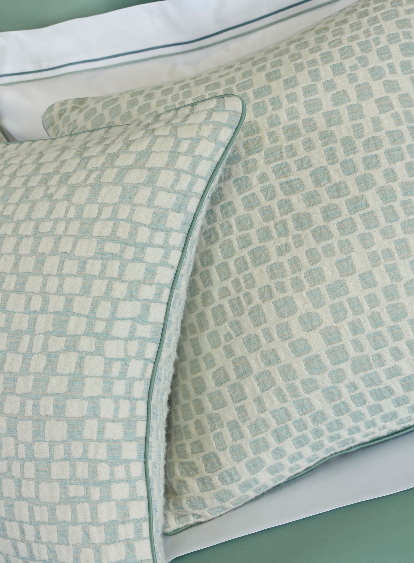 A close-up view of two pillow covers with a textured, geometric pattern in light blue and white, featuring the City Pillow Cover by Celso de Lemos available at Linen Society.