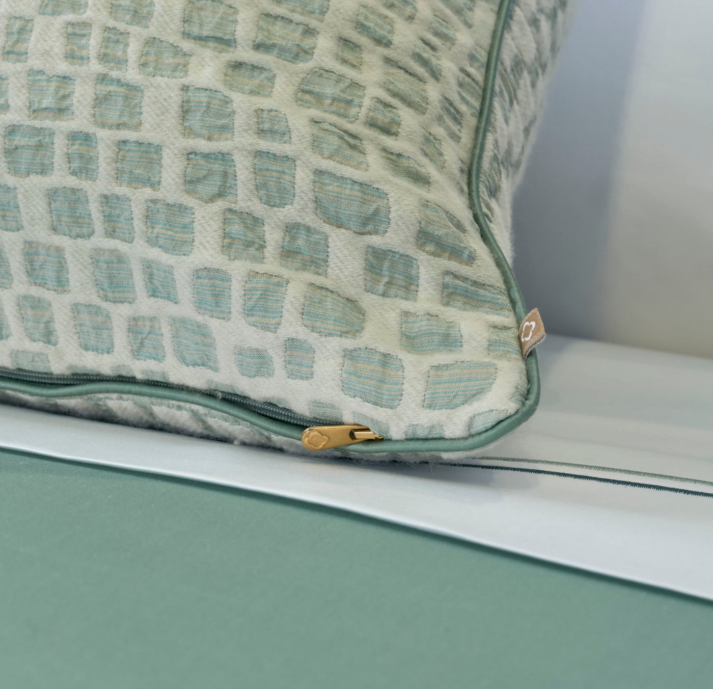 Close-up on a textured pillow with a geometric pattern in blue and cream hues, featuring the City Pillow Cover by Celso de Lemos available at Linen Society.